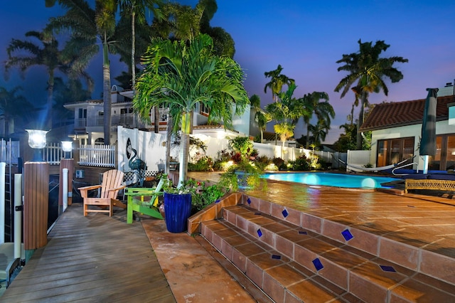 pool at dusk with a wooden deck