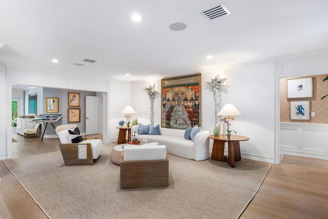 living room with crown molding and light hardwood / wood-style flooring