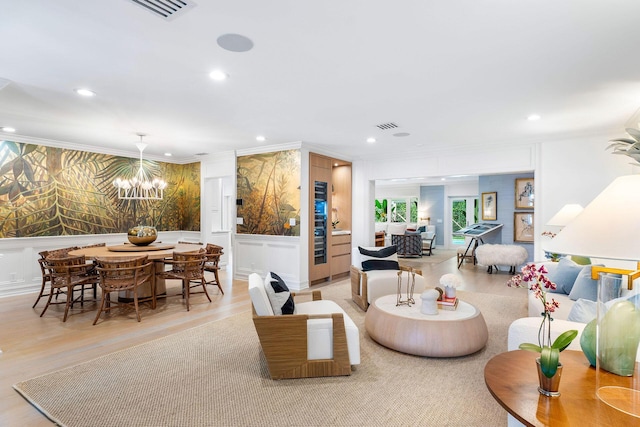 living room with ornamental molding, light hardwood / wood-style floors, and a notable chandelier