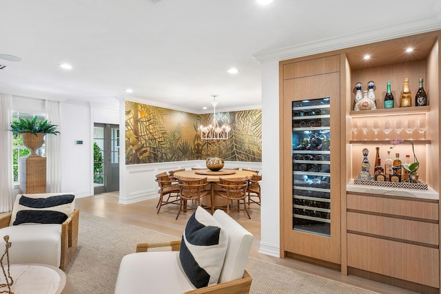 bar with a notable chandelier, decorative light fixtures, crown molding, and light hardwood / wood-style flooring