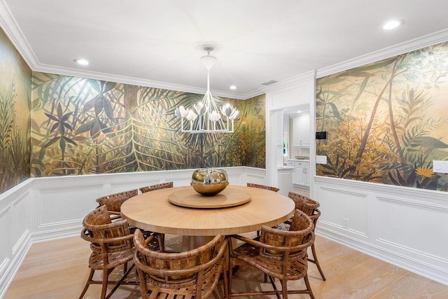 dining space featuring crown molding, a chandelier, and light wood-type flooring