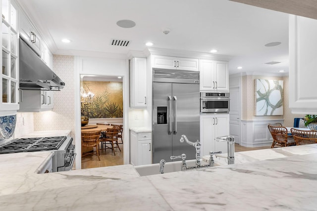 kitchen with white cabinets, sink, decorative backsplash, light stone counters, and stainless steel appliances