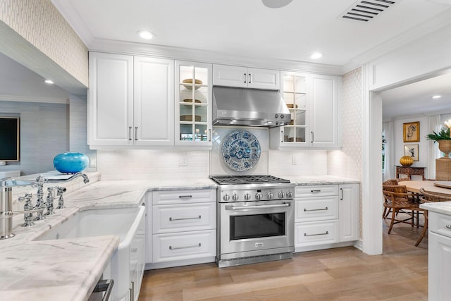 kitchen with white cabinets, high end stove, and crown molding