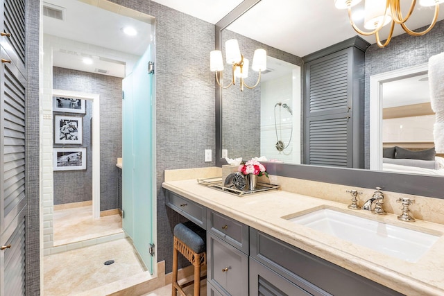 bathroom with a chandelier, vanity, and tiled shower