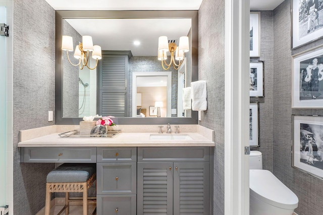 bathroom featuring toilet, vanity, and an inviting chandelier