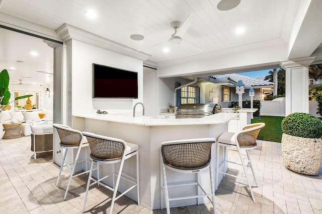 view of patio featuring exterior kitchen, area for grilling, a wet bar, and ceiling fan