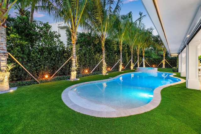 pool at dusk featuring a lawn