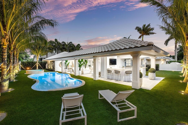 pool at dusk featuring a lawn, a bar, and a patio