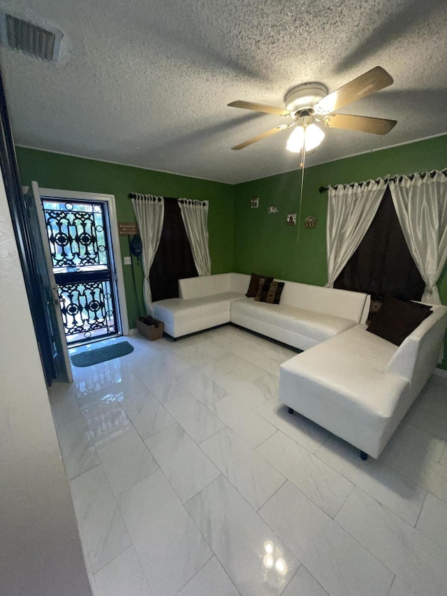 living room featuring ceiling fan and a textured ceiling