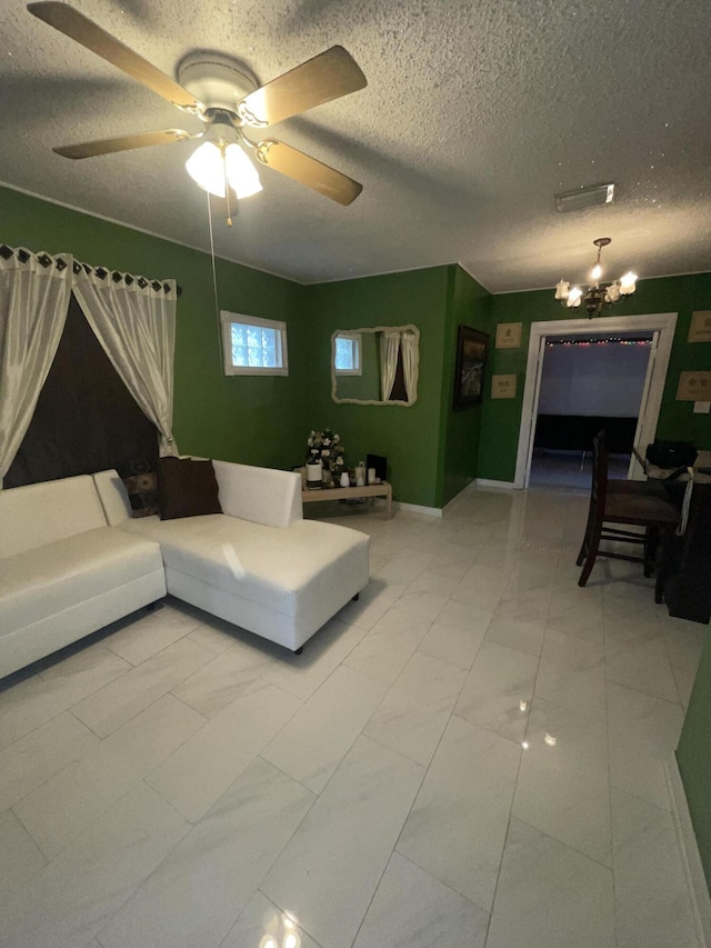 living room featuring ceiling fan with notable chandelier and a textured ceiling