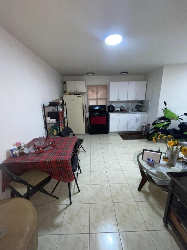 kitchen featuring white refrigerator, white cabinetry, and black range oven