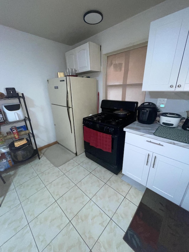 kitchen with white cabinetry, white refrigerator, light tile patterned floors, and black range with gas stovetop