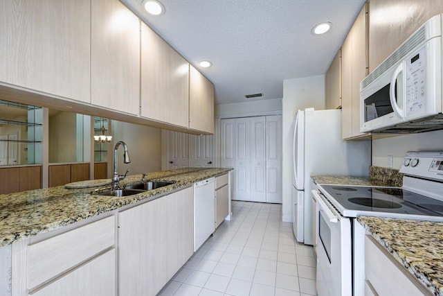 kitchen featuring light stone countertops, white appliances, a textured ceiling, sink, and light tile patterned floors