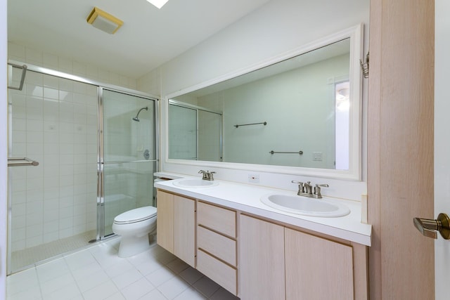 bathroom with tile patterned floors, vanity, toilet, and a shower with door