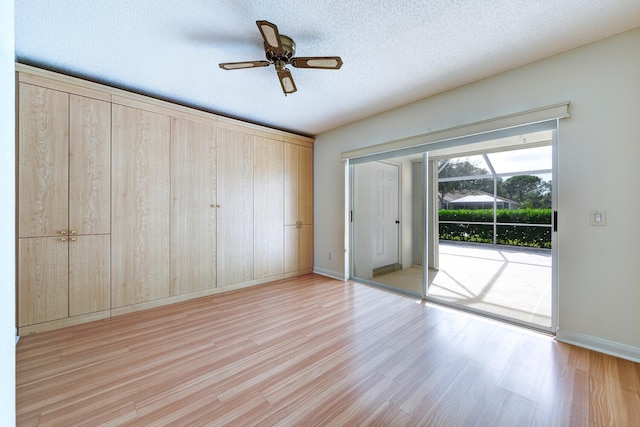 unfurnished bedroom with light wood-type flooring, a textured ceiling, access to outside, and ceiling fan