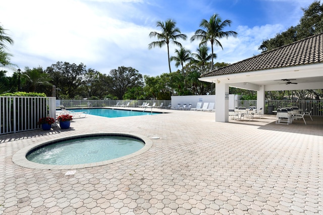 view of swimming pool with ceiling fan, a community hot tub, and a patio