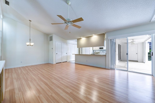 unfurnished living room with ceiling fan with notable chandelier, light wood-type flooring, lofted ceiling, and a textured ceiling