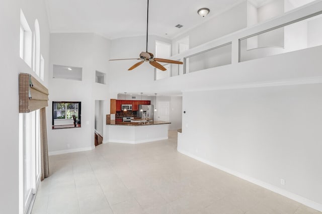 unfurnished living room featuring ceiling fan, light tile patterned floors, and a towering ceiling