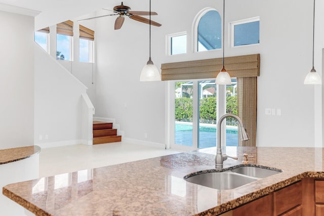 kitchen with ceiling fan, light stone countertops, sink, and plenty of natural light