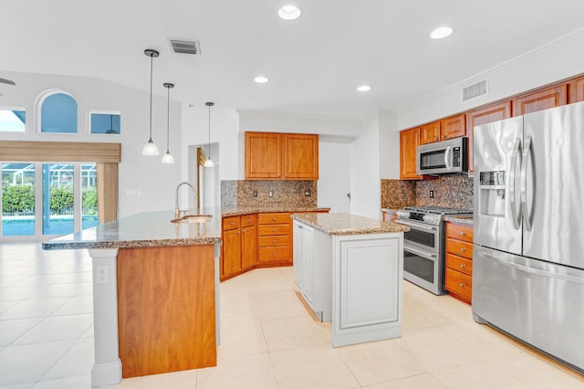 kitchen featuring a center island with sink, appliances with stainless steel finishes, backsplash, hanging light fixtures, and sink