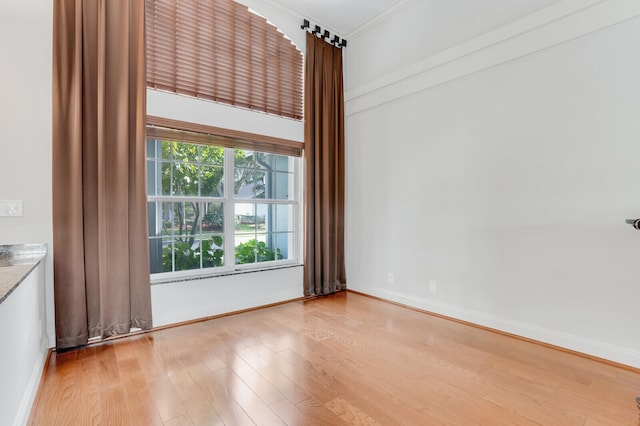 unfurnished room with crown molding and light wood-type flooring