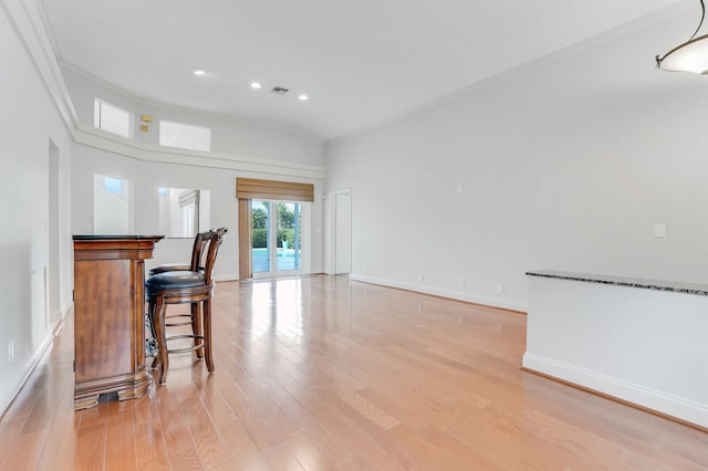 living room with light wood-type flooring, ornamental molding, and vaulted ceiling