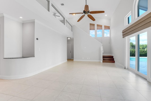 unfurnished living room with ceiling fan, a high ceiling, crown molding, and light tile patterned flooring