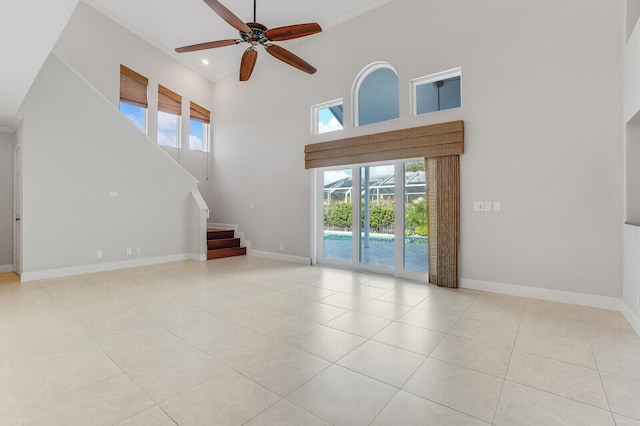 unfurnished living room featuring ceiling fan, a high ceiling, and light tile patterned flooring