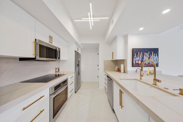 kitchen with light stone counters, white cabinetry, sink, and appliances with stainless steel finishes