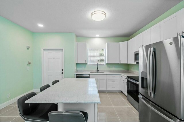 kitchen featuring light tile patterned flooring, white cabinets, and stainless steel appliances