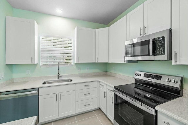 kitchen with a kitchen breakfast bar, stainless steel appliances, sink, light tile patterned floors, and white cabinets