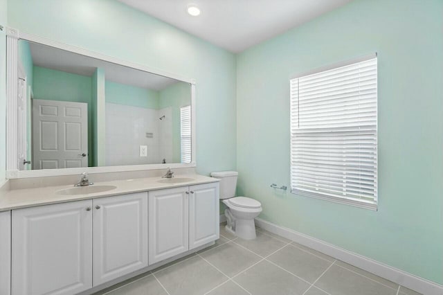 bathroom with toilet, vanity, tile patterned floors, and a wealth of natural light