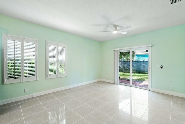 spare room featuring ceiling fan, light tile patterned floors, and a wealth of natural light