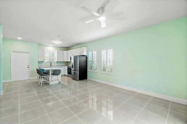 kitchen featuring a breakfast bar, stainless steel refrigerator with ice dispenser, ceiling fan, a wealth of natural light, and white cabinetry