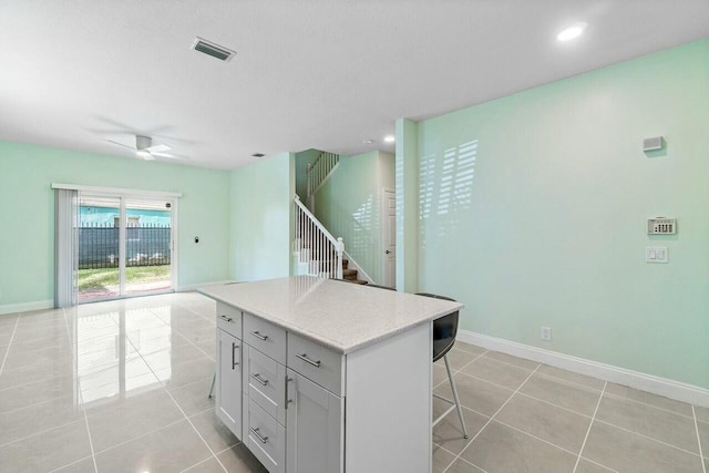 kitchen featuring ceiling fan, a center island, a kitchen bar, and light tile patterned floors