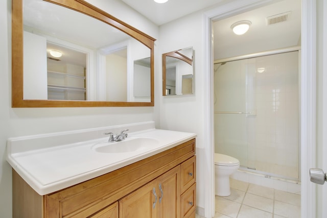 bathroom featuring toilet, tile patterned flooring, a shower with shower door, and vanity