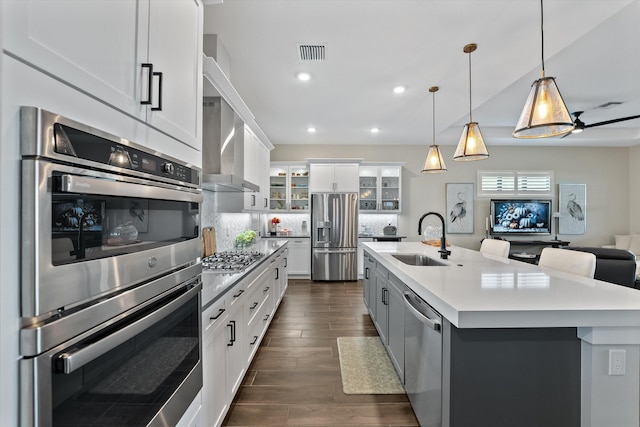 kitchen featuring appliances with stainless steel finishes, tasteful backsplash, sink, a center island with sink, and white cabinetry