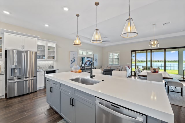 kitchen featuring pendant lighting, a kitchen island with sink, sink, decorative backsplash, and stainless steel appliances