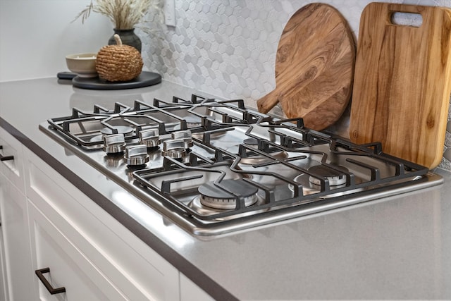 interior details featuring white cabinets, decorative backsplash, and stainless steel gas cooktop