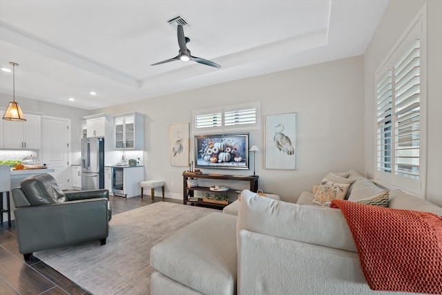 living room with a tray ceiling and ceiling fan