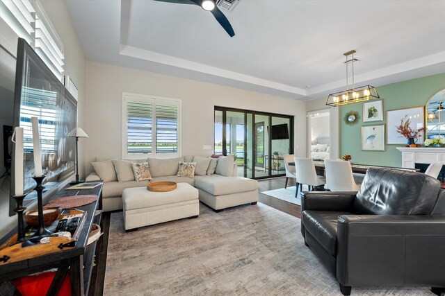 living room with a tray ceiling, ceiling fan, and light hardwood / wood-style floors