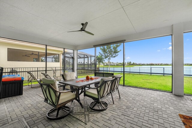 sunroom / solarium with ceiling fan and a water view