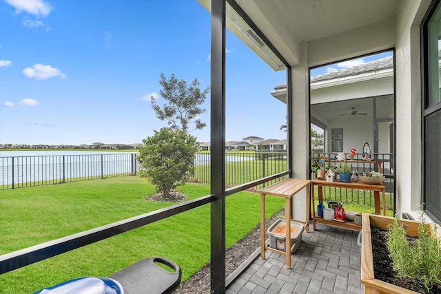 sunroom featuring ceiling fan and a water view