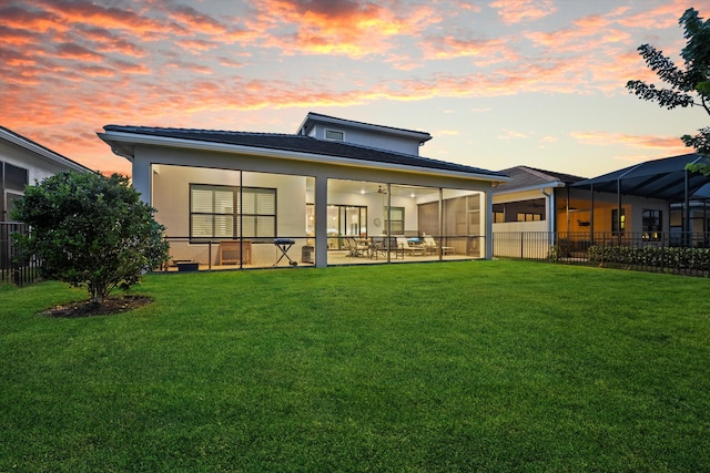 back house at dusk with a lawn and a patio