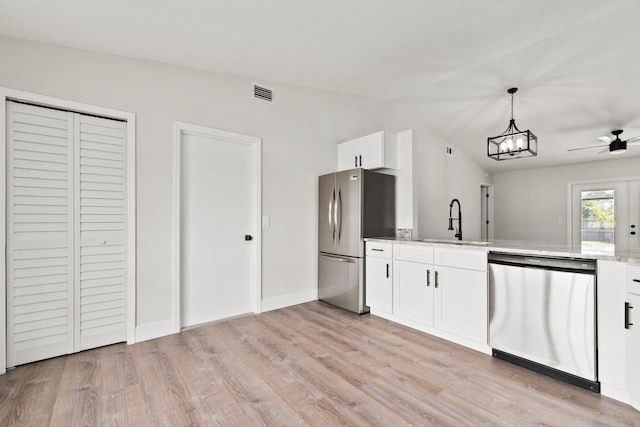 kitchen featuring stainless steel appliances, vaulted ceiling, sink, pendant lighting, and white cabinetry