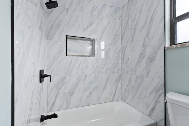 bathroom featuring toilet and tiled shower / bath