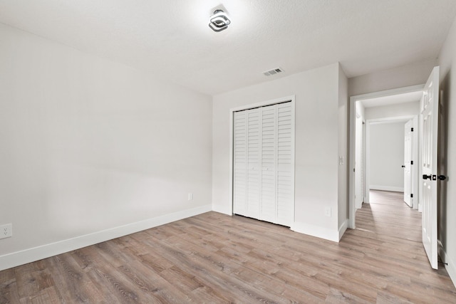 unfurnished bedroom featuring light hardwood / wood-style flooring and a closet