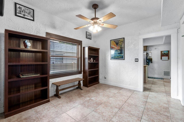 tiled empty room with a textured ceiling and ceiling fan