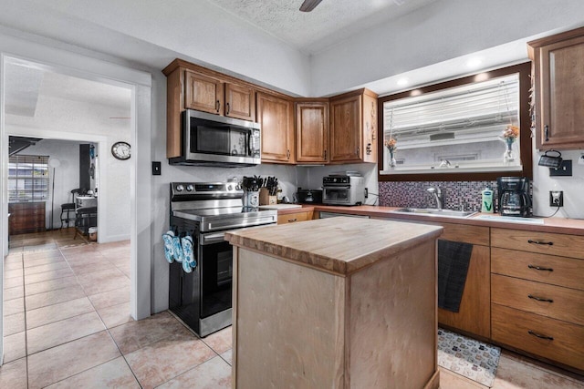 kitchen featuring a center island, sink, a textured ceiling, appliances with stainless steel finishes, and butcher block counters