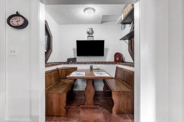 dining area featuring dark tile patterned floors and a textured ceiling